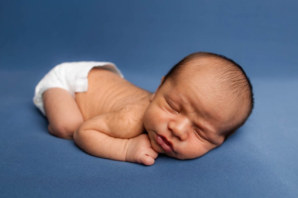 Baby posed on professional backdrop stand during in-home newborn session