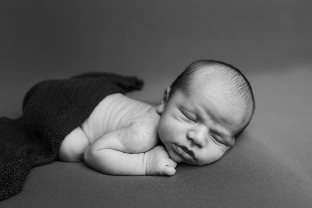 Studio-style newborn portrait with neutral backdrop and soft wrap in Nashville home
