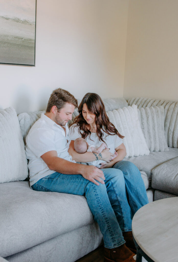 Family cuddling on couch in bright, airy home during lifestyle photoshoot