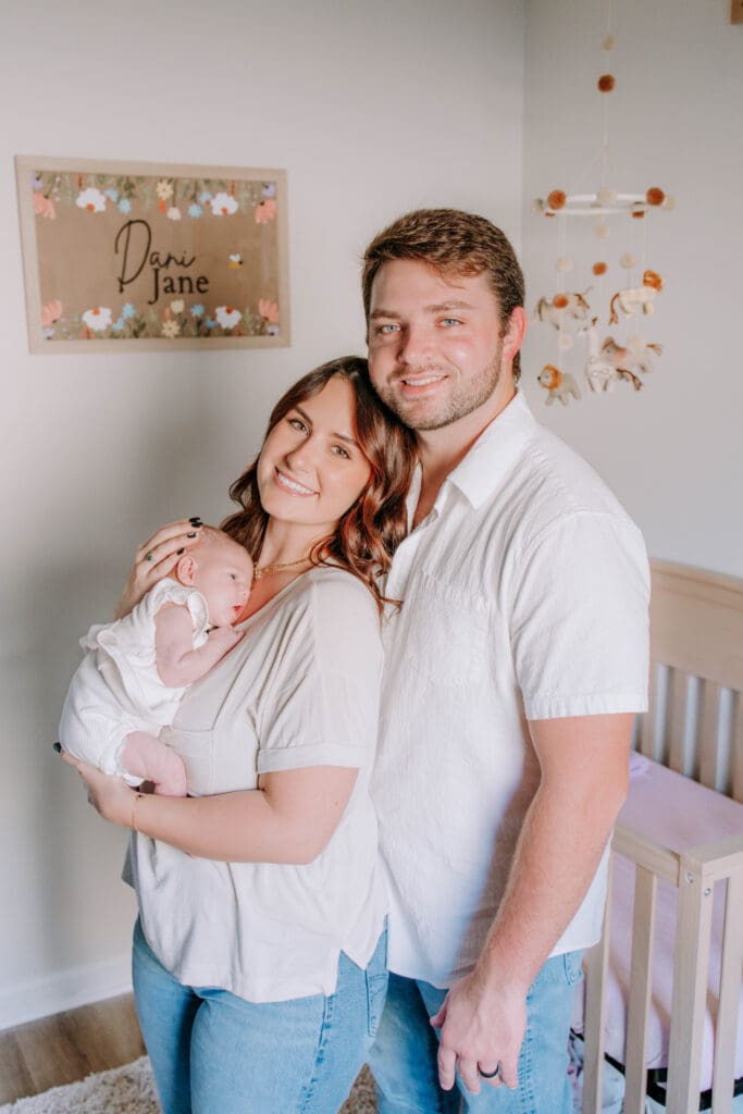 Mother holding newborn in softly lit bedroom during dreamy lifestyle session