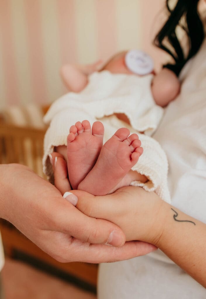 mom and dad holding baby feet during at-home photography in Nashville