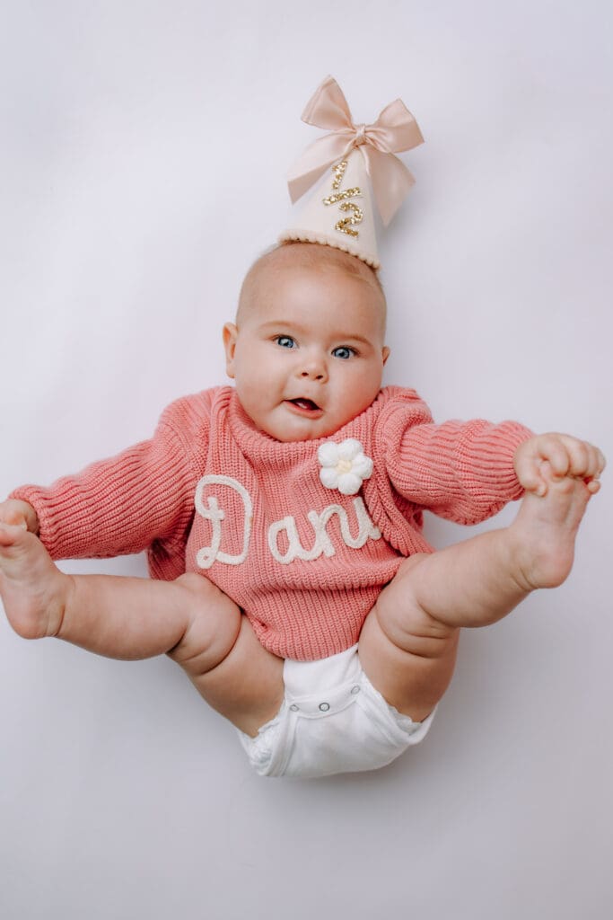 6 month baby laying down with 1/2 party hat for Nashville milestone photoshoot